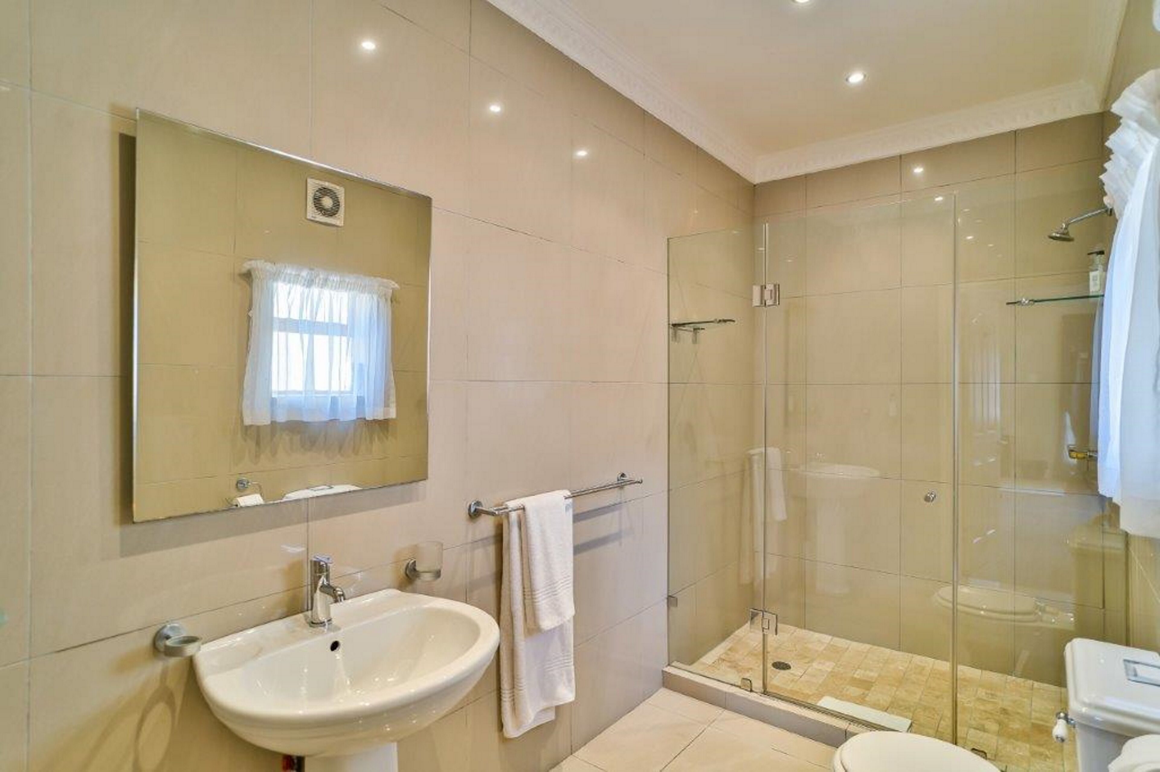 A modern bathroom with a glass-enclosed shower, a sink, and a toilet.