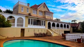 A two-story house with a swimming pool, outdoor furniture, and a staircase leading to a balcony. - Albion Manor (Durban)