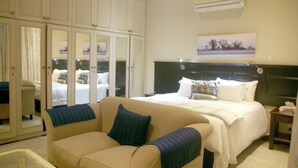 A hotel room with a large bed, a sofa, a desk, and a wardrobe. - Albion Manor (Durban)