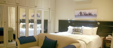 A hotel room with a large bed, a sofa, a desk, and a wardrobe.