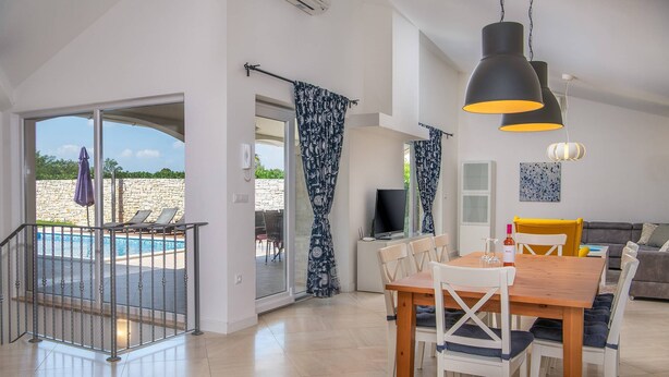Uma sala de estar ampla com vista para a piscina, uma mesa de jantar e um sofá.