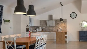 Cozinha moderna com armários brancos, ilha central e iluminação pendente.