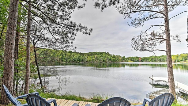 A lakeside deck with Adirondack chairs and a dock extending into the water. - Quiet Retreat on Lake w/ Kayaks, Boats + Bikes! (Wautoma)