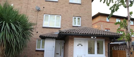 A two-story brick apartment with a small attached garage, a satellite dish, and a potted plant.