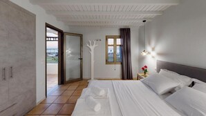 Een hotelkamer met een bed, een nachtkastje met een bloevas, een raam met gordijnen en uitzicht op de omgeving.