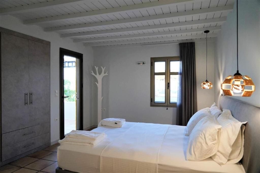 Ein Schlafzimmer mit Bett, Kleiderschrank, Fenster und Tür.