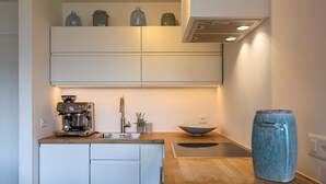 Una cocina moderna con una cafetera espresso integrada, un lavabo y un jarrón azul grande en la encimera.