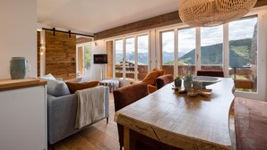 Cocina moderna con una mesa de madera, un sofá y un televisor mostrando 'NETFLIX'.