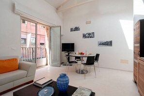 Un salon moderne comprenant un canapé, une table basse, une table à manger avec des chaises, un téléviseur et un balcon offrant une vue sur les immebles.