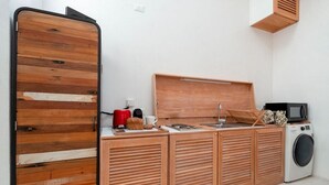 A compact kitchen with a wooden countertop, a microwave, a coffee maker, and a washing machine.