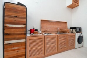 A compact kitchen with a wooden countertop, a microwave, a coffee maker, and a washing machine.