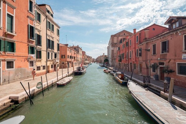 A canal with boats docked, buildings on either side, and a clear sky.