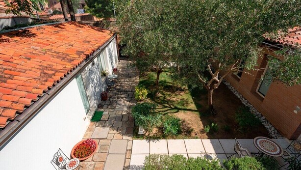 A courtyard with a tiled roof, a small garden area with a tree, and outdoor seating.
