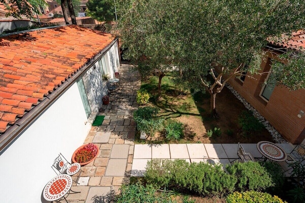 A courtyard with a tiled roof, a small garden area with a tree, and outdoor seating.