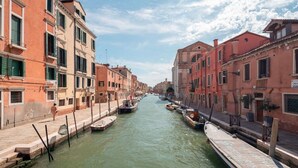 A canal lined with historic buildings, narrow waterway, and boats docked along the sides.
