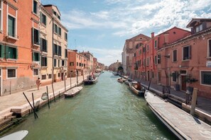 A canal lined with historic buildings, narrow waterway, and boats docked along the sides.