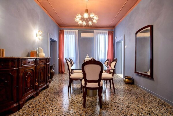 A dining area with a round table, chairs, a chandelier, and a cabinet.