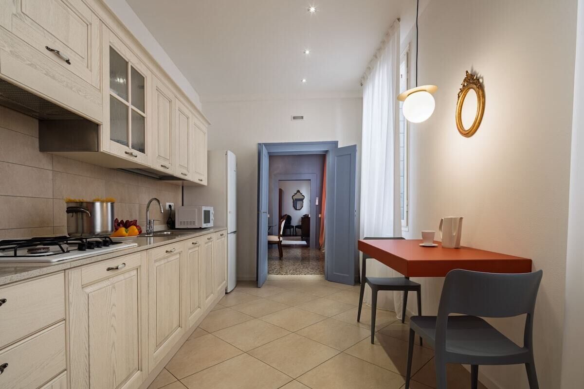 A kitchen with cabinets, a stove, and a dining area with a table and chairs.