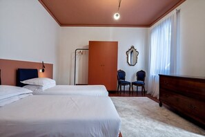 A hotel room with two beds, a wardrobe, a mirror, and a window with curtains.
