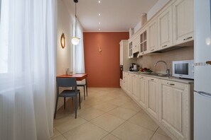 A kitchen with white cabinets, a microwave, and a dining area with a table and chairs.