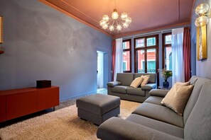 A living room with a sofa set, a red cabinet, and a decorative light fixture.