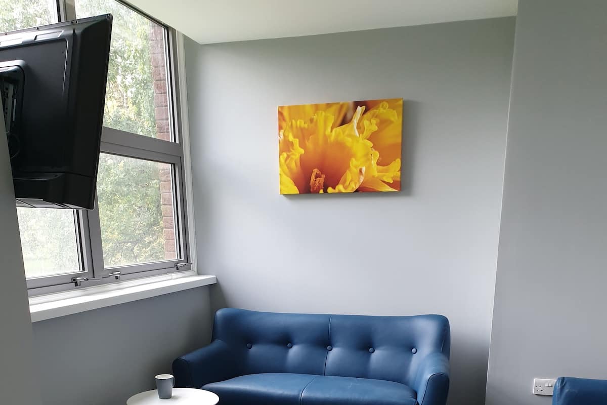 A modern room with a blue sofa, a small round table, and a television mounted on the wall.