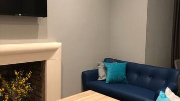 Una sala de estar moderna con un sofá azul, una mesa de centro de madera y una chimenea.