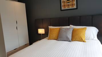 Une chambre d’hôtel avec un lit, une table de chevet, une lampe et un tableau encadré au mur.