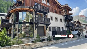 A multi-story chalet with balconies, large windows, and a stone facade.