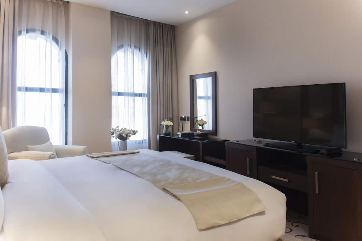 Ein Hotelzimmer mit einem großen Bett, einem Fernseher, einem Schreibtisch und einem Sessel.