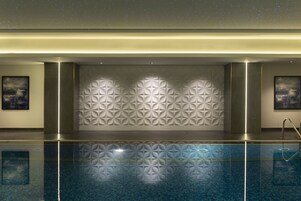 A modern indoor pool area with geometric wall patterns and a clear pool surface.