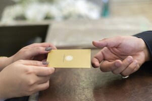 Two hands exchanging a small card with a logo.