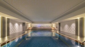 Una piscina interior moderna con techo estrellado, patrones geom étricos en las paredes y una zona de estar central.