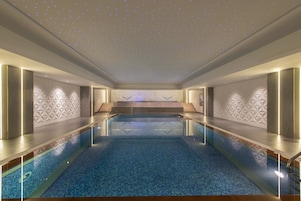 A modern indoor pool with a starry ceiling, geometric wall patterns, and a central seating area.