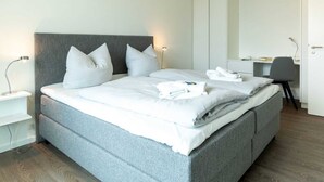 Ein modernes Hotelzimmer mit einem großen Bett, einem Schreibtisch und einem Kleiderschrank.