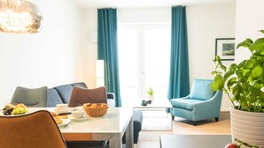 Ein modernes Wohnzimmer mit Essbereich, ausgestattet mit einer Couch, einem Esstisch mit einem Brotkorb und einer Topfpflanze.