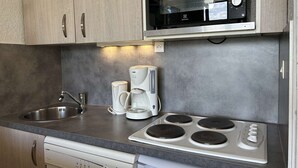 A kitchenette with a microwave, coffee maker, and stove.
