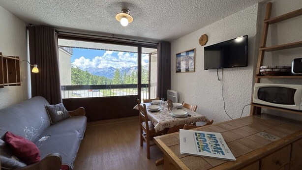 A cozy room with a sofa, dining table, and a TV.