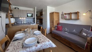 A compact living space with a kitchenette, dining area, and a sofa.