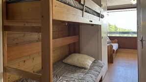 A bunk bed room with a window and a door.