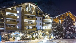 A multi-story hotel with balconies, a ski lodge, and a snow-covered tree. - Luxury 8-Person Apartment with Sauna, Parking, and Balcony in Central Val d'Isère (Val-d'Isère)