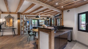 A rustic kitchen with wooden beams, a large island, and a view of the outdoors. - Luxury 8-Person Apartment with Sauna, Parking, and Balcony in Central Val d'Isère (Val-d'Isère)
