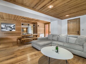 A modern living room with wooden flooring, a grey sofa, a round white coffee table, and a wooden ceiling.