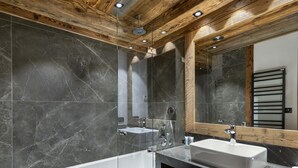 Une salle de bain moderne avec un plafond en bois, deux lavabos, une baignoire et un grand miroir.