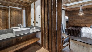 Une salle de bain moderne avec un grand miroir, des poutres en bois et un plan de toilette en marbre.