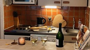 A kitchen with a microwave, a coffee maker, a bottle of wine, and glasses on the counter. - Apartment Montgenèvre 4 people, parking, ski-in/ski-out (Montgenèvre)