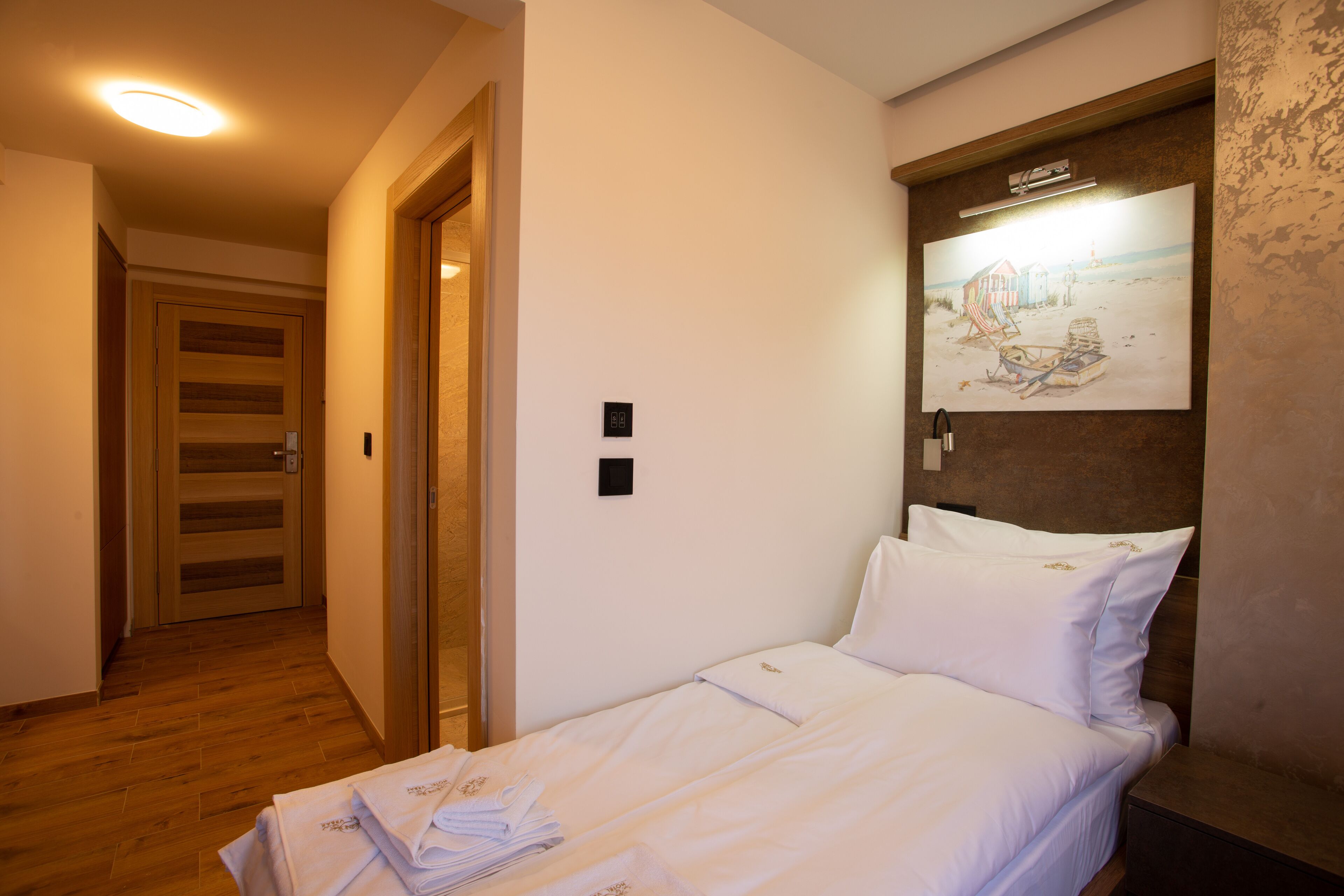 A hotel room with a bed, a wall-mounted artwork, and a wooden floor.