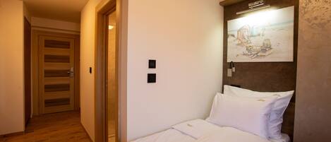 A hotel room with a bed, a wall-mounted artwork, and a wooden floor.