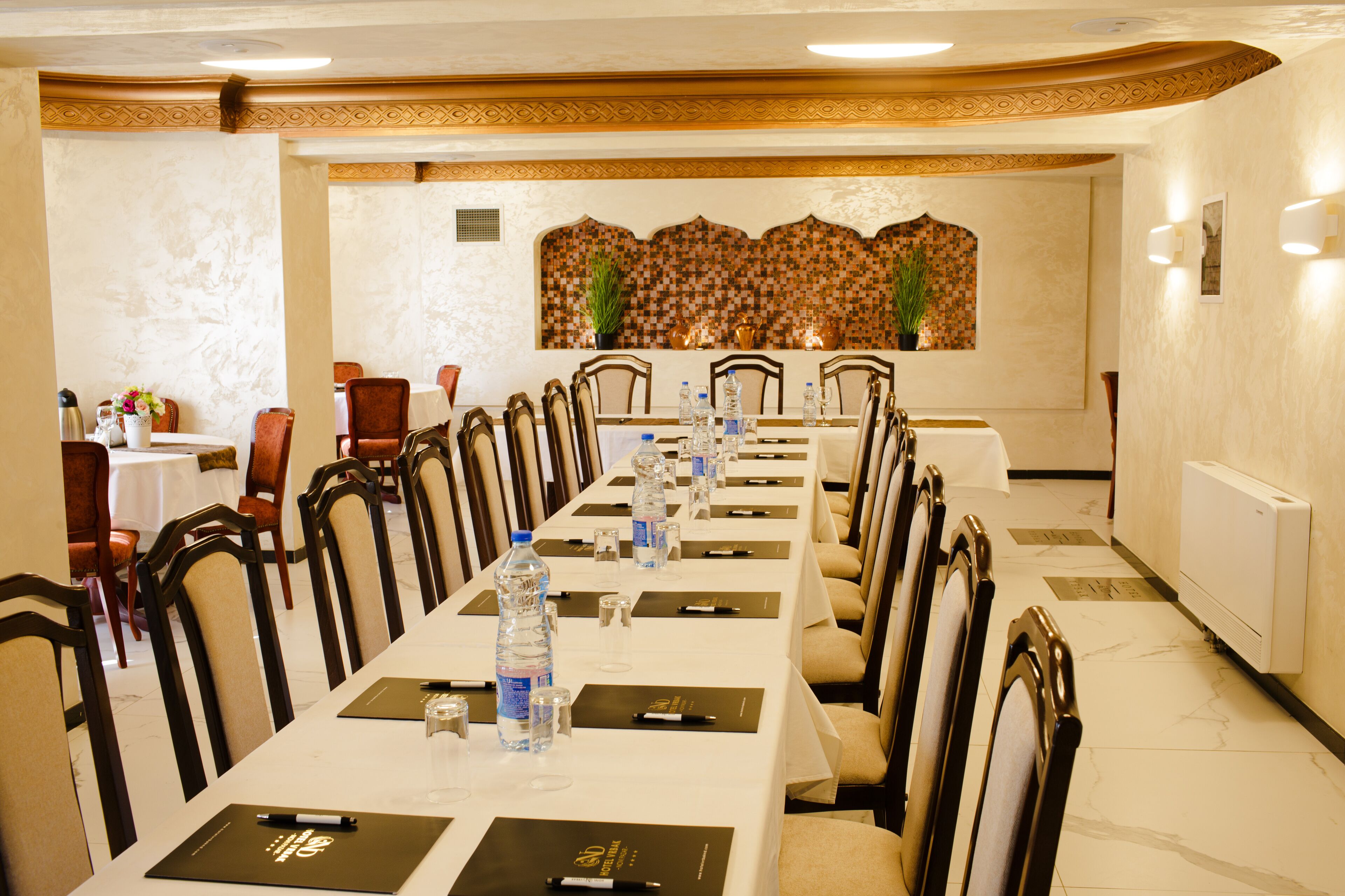 Une salle de conférence avec une longue table, des chaises, des bouteilles d’eau et des plaques nominatives.