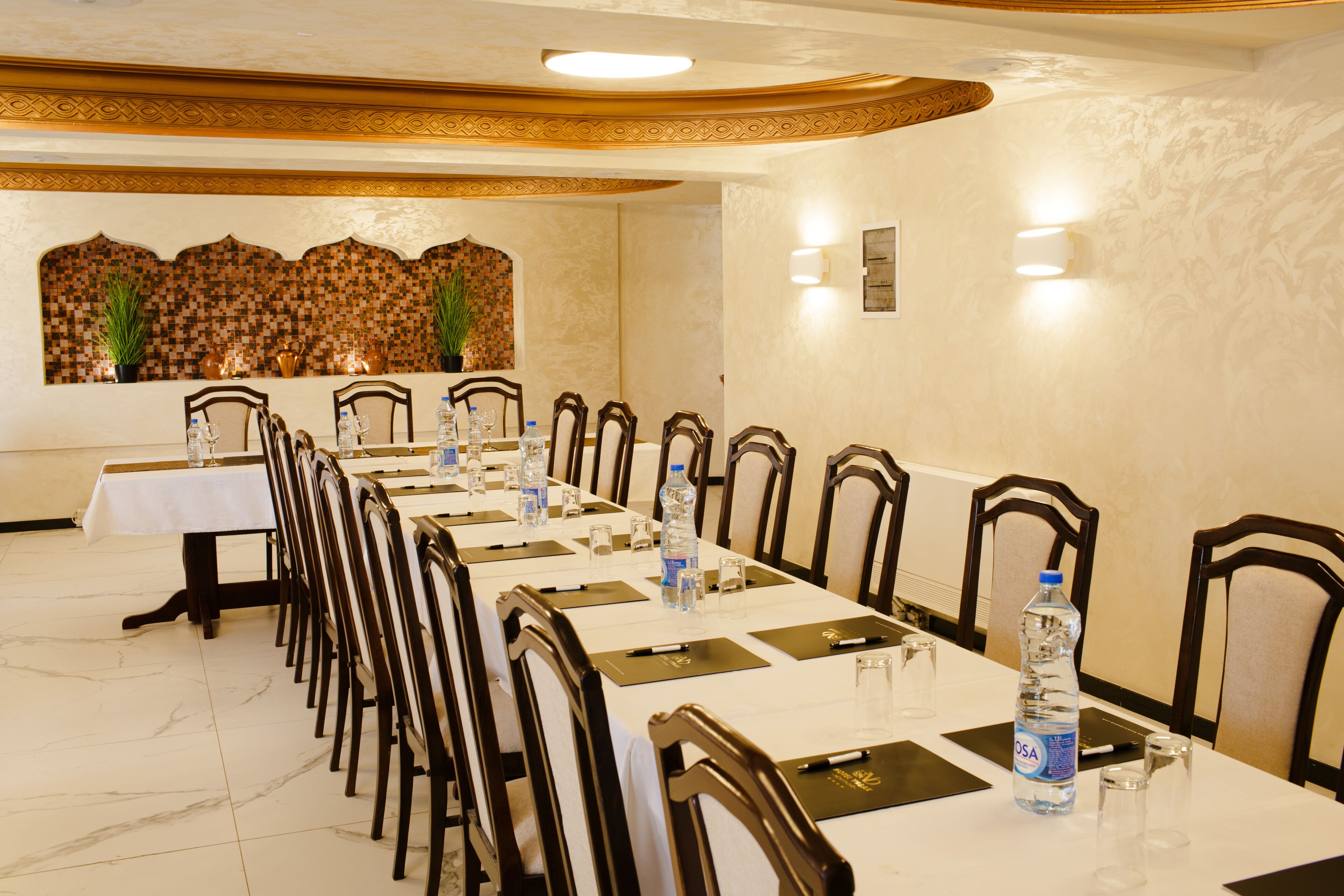 A conference room with a long table, chairs, water bottles, and a decorative wall.